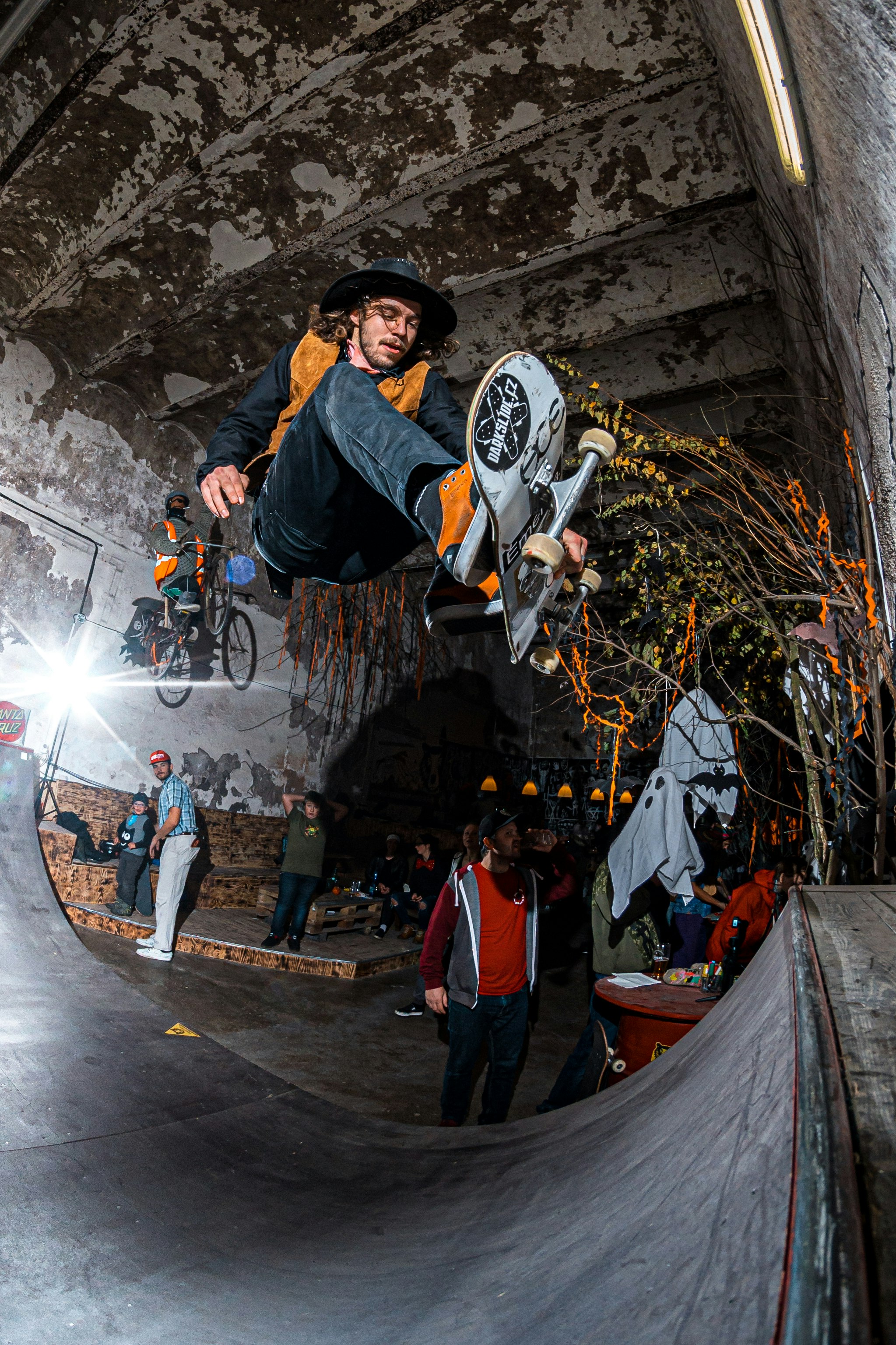 man wearing gray and yellow dress shirt and blue jeans ramping skateboard trick